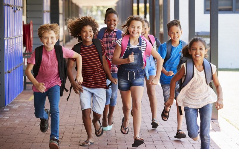 School kids running in elementary school hallway, front view